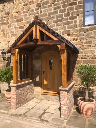 Reclaimed oak porch with a pitched roof, dark wooden beams and dwarf wall.