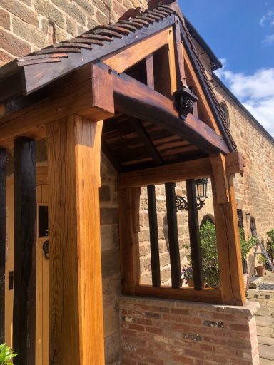 Reclaimed oak porch with a pitched roof, dark wooden beams and dwarf wall.